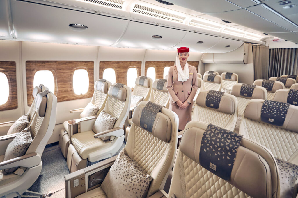 an emirates cabin crew standing in a premium economy cabin