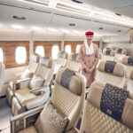 an emirates cabin crew standing in a premium economy cabin
