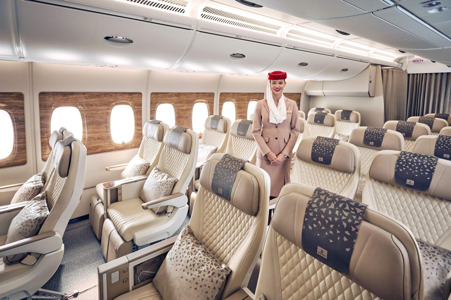 an emirates cabin crew standing in a premium economy cabin