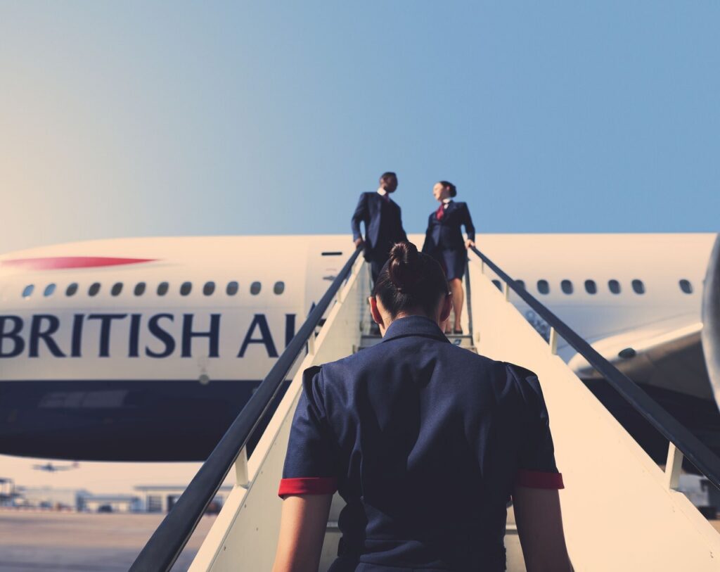 a british airways cabin crew member walking up airstairs to a plane
