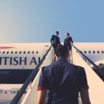 a british airways cabin crew member walking up airstairs to a plane
