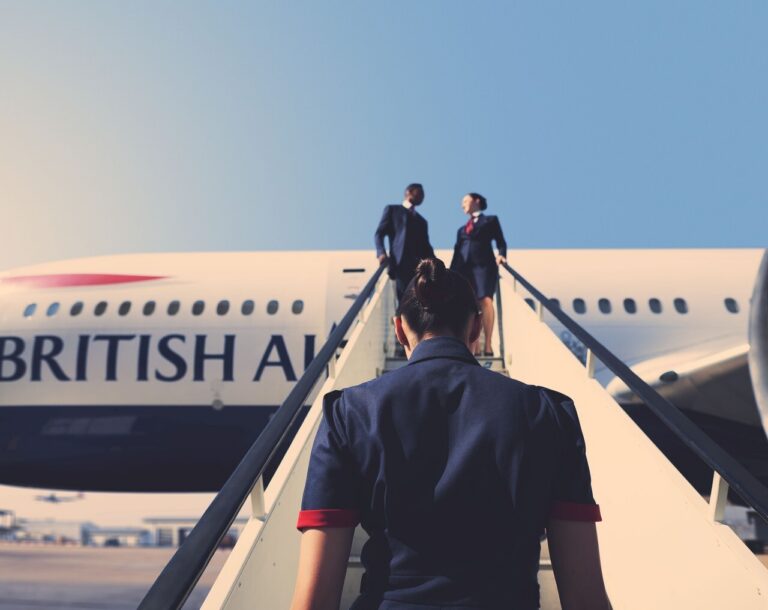 a british airways cabin crew member walking up airstairs to a plane