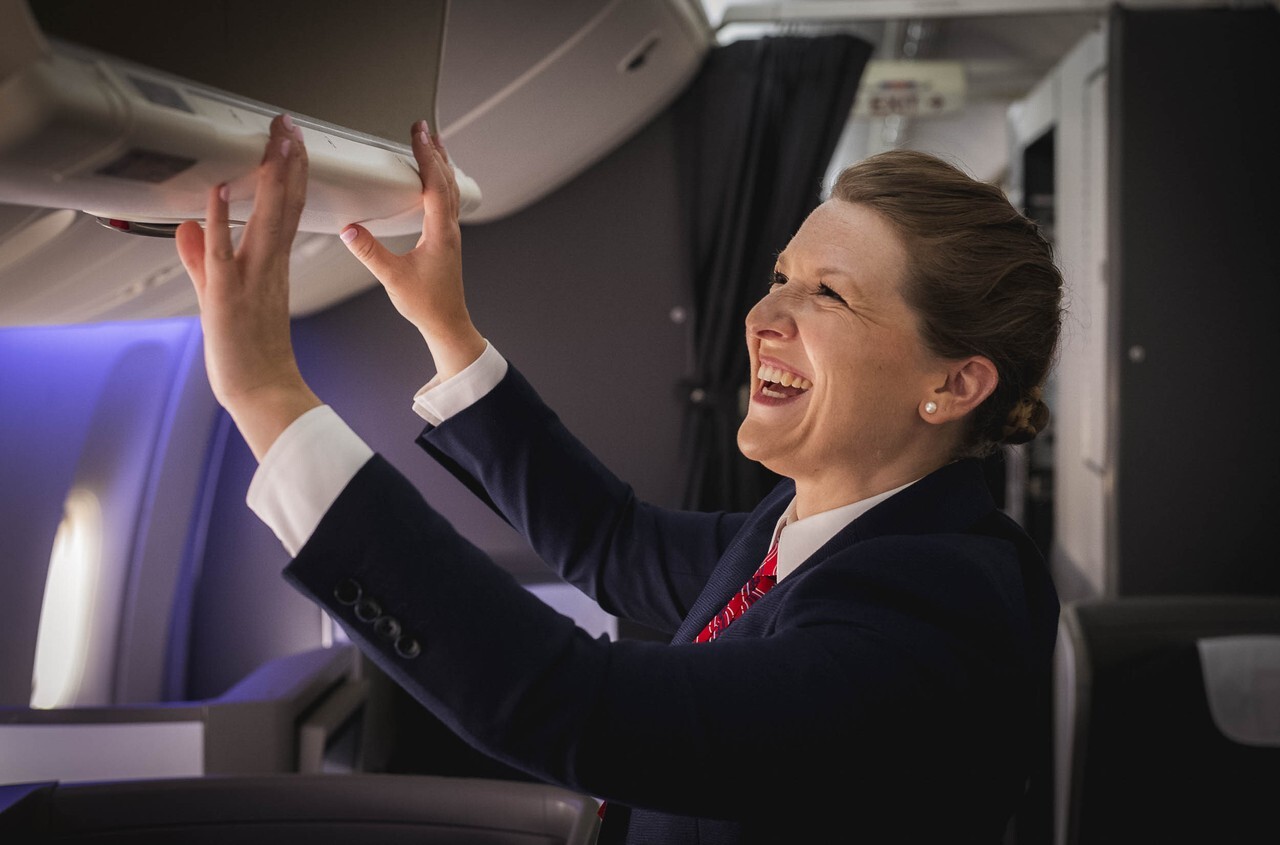 A british Airways cabin crew member closing a hat rack
