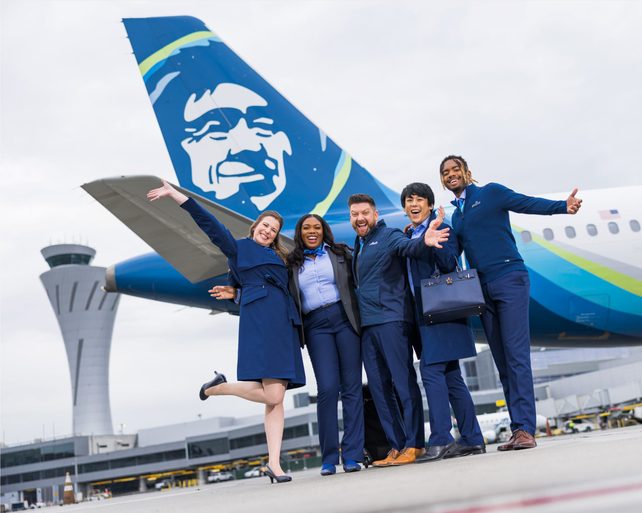 Alaska Airlines flight attendants pose in front of an Alaska Airlines plane