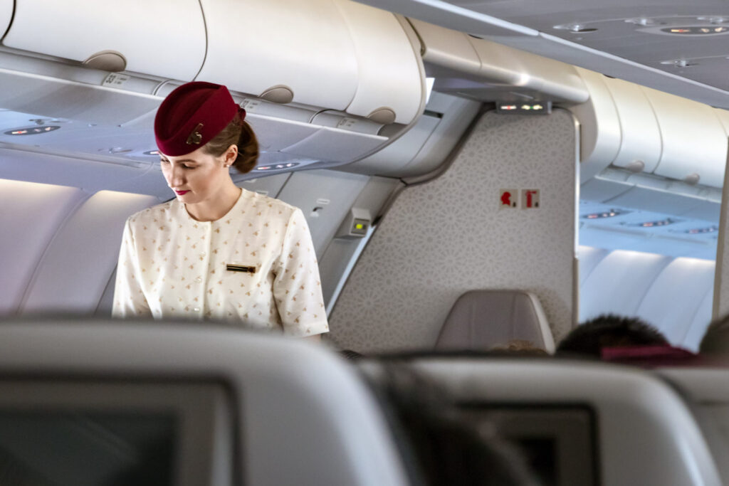 a member of qatar airways cabin crew standing in the aisle