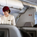 a member of qatar airways cabin crew standing in the aisle